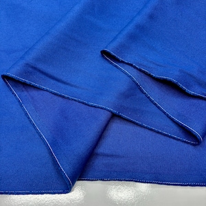 Puede incluir: Primer plano de una tela azul vibrante con textura visible. La tela est&aacute; doblada, revelando los bordes con costuras blancas. La apariencia general sugiere un material textil, posiblemente para ropa o decoraci&oacute;n del hogar.