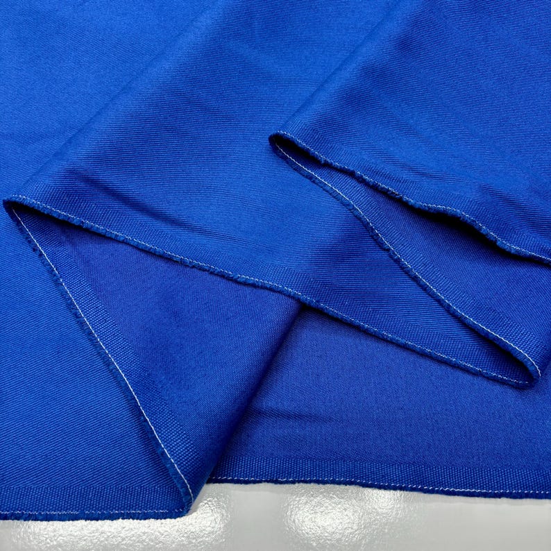 Puede incluir: Primer plano de una tela azul vibrante con textura visible. La tela est&aacute; doblada, revelando los bordes con costuras blancas. La apariencia general sugiere un material textil, posiblemente para ropa o decoraci&oacute;n del hogar.
