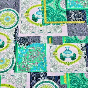 May include: A vibrant fabric featuring a patchwork design with ornate patterns. The design incorporates elements like floral motifs, medallions, and geometric shapes in shades of green, pink, and blue. The fabric has a luxurious feel.