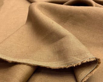 May include: Close-up of a tan-colored fabric with a textured weave. The fabric is folded, creating soft shadows and highlighting the frayed edge. The material appears to be linen or a similar natural fiber, suitable for apparel or home decor.