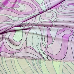 Puede incluir: Primer plano de una tela con un diseño abstracto y ondulado. La tela presenta un degradado de tonos rosa y blanco, con contornos negros. La tela tiene un aspecto suave y fluido, con un borde sin rematar visible en la parte inferior.