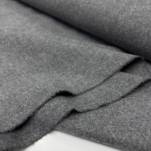May include: Close-up of a roll of gray fabric with a soft, textured surface. The fabric is folded and layered, revealing the raw, unfinished edges. The color is a medium gray.