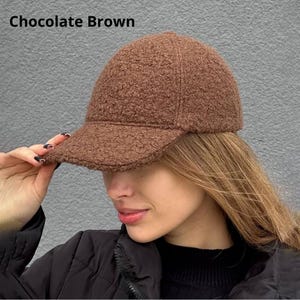 May include: Chocolate brown baseball cap with a textured, fuzzy fabric. The cap has a curved brim and a classic six-panel design. The text "Chocolate Brown" is visible in the image.