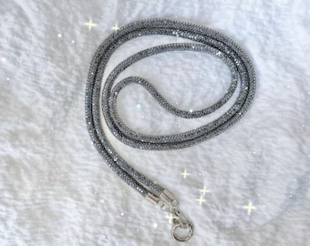 Cordón para teléfono con cristales plateados brillantes: elegante y práctico con cierre magnético.