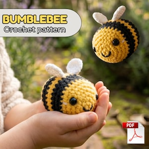 May include: Two crocheted bumblebees, one held in cupped hands, the other floating in the air. The bees are yellow and black with white wings and black eyes. The text "BUMBLEBEE Crochet pattern" is in a yellow and white banner.