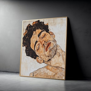 May include: A framed artwork featuring a portrait of a person with closed eyes and a slight smile. The artwork is rendered in warm brown and beige tones, with a gold frame. The subject has dark curly hair and a light beard.
