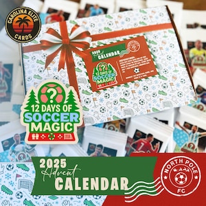 May include: A 2025 Advent Calendar box with a red ribbon and bow, featuring a soccer theme. The box is decorated with soccer balls, gloves, and flags. The text "12 Days of Soccer Magic" is prominently displayed, along with the Carolina Elite Cards logo.