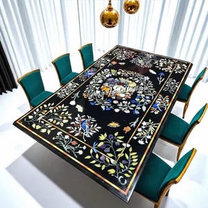 Puede incluir: Una mesa de comedor rectangular negra con intrincados diseños florales incrustados en varios colores. La mesa está rodeada por ocho sillas verdes tapizadas con marcos dorados. Encima, tres lámparas colgantes doradas iluminan la escena.