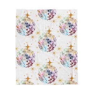 May include: White blanket with a repeating pattern of colorful disco balls and gold starbursts. The disco balls are made up of small, square tiles in shades of pink, blue, green, and yellow.