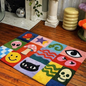 May include: A colorful, rectangular rug with a patchwork design. The rug features squares with various whimsical images, including a smiley face, a mushroom, an alien, a cat, and a skull. The rug is placed on a wooden floor.
