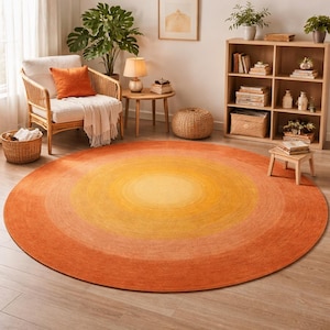 May include: A large, round rug with a gradient design in shades of orange and yellow. The rug is the focal point of a living room setting, with a woven chair, side table, and bookshelf in the background.