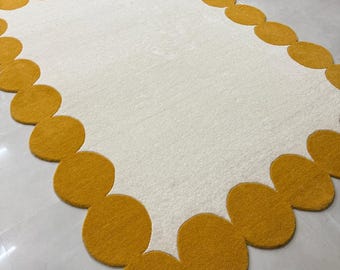Alfombra de lana tejida a mano, centro color crema, borde festoneado color mostaza