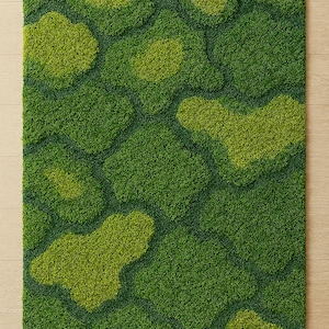 May include: A rectangular moss rug with a textured surface. The rug features a pattern of varying shades of green, with lighter green patches scattered across a darker green base. The rug is placed on a light-colored wooden floor.