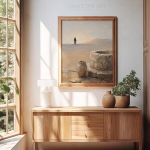 a serene indoor setting with a wooden cabinet, a painting of a desert landscape, and a lamp on a table.