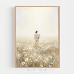 Könnte beinhalten: Ein gerahmter Kunstdruck zeigt eine Figur in einem weißen Gewand, die ein Lamm hält, in einem Feld weißer Gänseblümchen. Das Kunstwerk hat eine weiche, ätherische Qualität mit warmem, goldenem Licht. Der Text "GRACE INK ART" befindet sich unten.