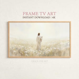 Könnte beinhalten: Ein gerahmter Druck, der eine Figur in einem weißen Gewand zeigt, die ein Lamm hält und durch ein Feld weißer Blumen geht. Der Text "FRAME TV ART" und "INSTANT DOWNLOAD | 4K" ist oben zu sehen. Das Kunstwerk ist in einem Holzrahmen.