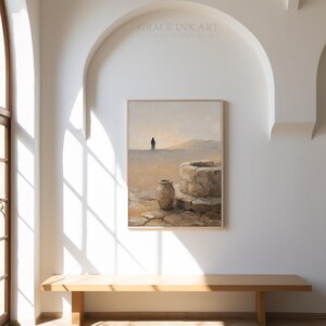 a large painting of a desert landscape hanging on a white wall, with a wooden bench in front of it.