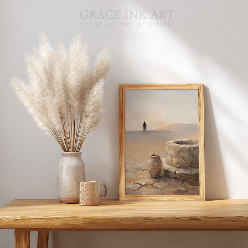 a wooden table with a vase of white flowers, a coffee mug, and a framed painting depicting a desert landscape with a well and a solitary figure.