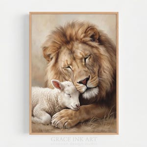 May include: A framed wall art print featuring a painting of a large, golden-brown lion resting with its head against a small, white lamb. Both animals have their eyes closed. The text GRACE INK ART is printed at the bottom of the frame.