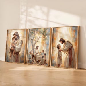 May include: A set of three framed art prints depicting religious scenes. The artwork shows a figure in a white robe with long hair interacting with children. The paintings have a warm colour palette with gold and brown tones, and are set in wooden frames.