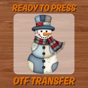 May include: A DTF transfer featuring a patchwork snowman design. The snowman has a carrot nose, black button eyes, and a red and gray scarf. The text "READY TO PRESS" and "DTF TRANSFER" are in orange.