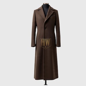 May include: A long, brown overcoat with a notched lapel, single-breasted button closure, and a chest pocket. The coat is displayed on a mannequin. The coat has a classic, tailored design.