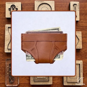 Puede incluir: Una cartera de cuero marrón con forma de calzoncillos, llena de dinero en efectivo. La cartera tiene un diseño único con costuras decorativas. Sellos de madera y el texto "Brandy Time" en el fondo.