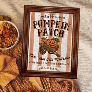 Pode incluir: Uma placa emoldurada com uma moldura de madeira marrom. A placa diz "Pumpkin Patch" com um gráfico de abóboras em um carrinho. O texto inclui "Pick Your Own Pumpkins" e "Open Daily 9AM-6PM".