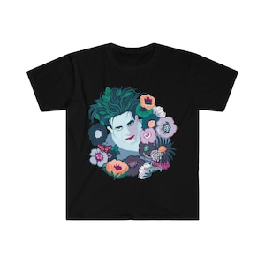 Könnte beinhalten: Schwarzes T-Shirt mit einem grafischen Druck eines Männergesichts, umgeben von bunten Blumen.