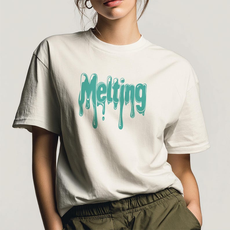 May include: Off-white t-shirt with the word "Melting" in turquoise, dripping font. The short-sleeved shirt is made of a soft material and is worn by a person. The person is wearing olive green pants.