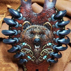 May include: A brown leather bear head wall hanging with black claws and turquoise accents.