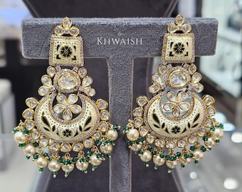 May include: A pair of gold-toned earrings with a square top and a crescent-shaped bottom. The earrings feature white enamel, clear crystals, and green and white bead accents. The text "KIIWAISH" is visible.