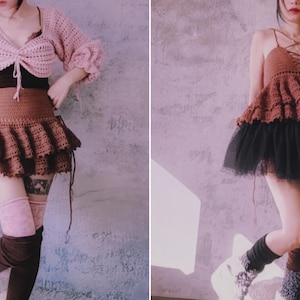 Puede incluir: Dos conjuntos de crochet hechos a mano. Uno presenta una rebeca corta rosa y una falda con volantes marrón. El otro es un top de crochet marrón con una falda de tul negra. Ambos conjuntos son únicos y elegantes.