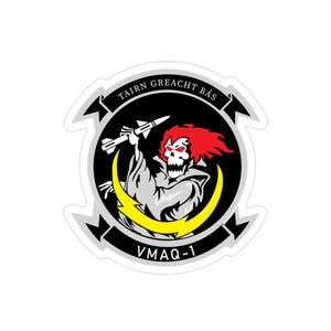 Peut inclure: Autocollant avec un emblème circulaire représentant une figure en forme de crâne aux cheveux rouges, tenant un missile. Un éclair jaune et le texte "TAIRN GREACHT BÁS" sont visibles. Le texte "VMAQ-1" est en bas.