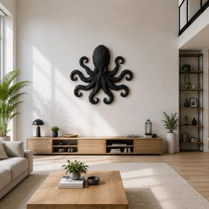 May include: A large, black, geometric octopus wall sculpture with a faceted, angular surface texture. The octopus is mounted centrally on a plain white wall above a long, light-toned wooden media console in a bright, open-concept living room.