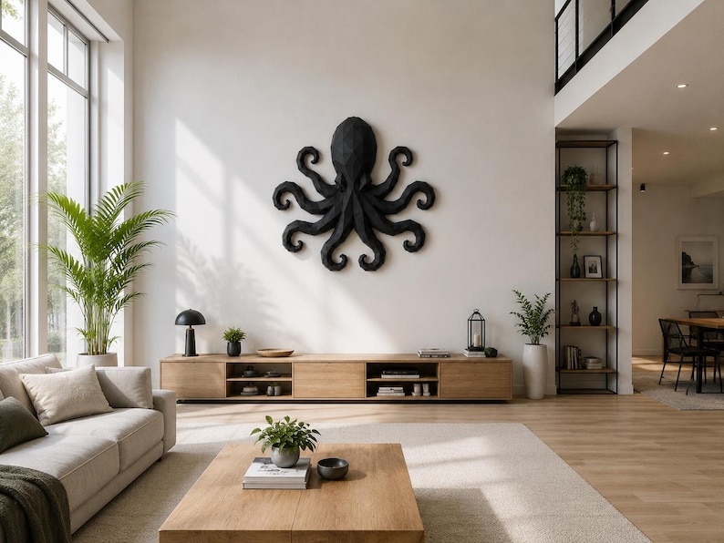 May include: A large, black, geometric octopus wall sculpture with a faceted, angular surface texture. The octopus is mounted centrally on a plain white wall above a long, light-toned wooden media console in a bright, open-concept living room.