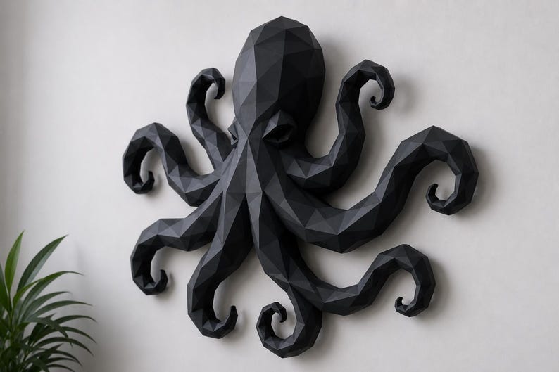 May include: A black wall-mounted octopus sculpture featuring a geometric, low-poly design with sharp, angular facets. The creature has a large central head and eight curved, multi-faceted tentacles extending outward in a symmetrical arrangement.