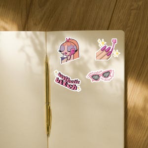 May include: A set of four vinyl stickers featuring a cartoon character on a phone, a hand applying pink nail polish, pink sunglasses with the text "I can't relate to desperation," and the text "aesthetic bitch" in a wavy pink font.