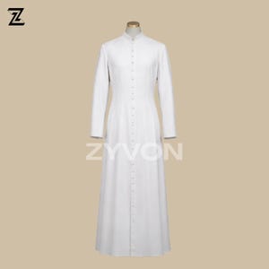 Pu&ograve; includere: Una lunga veste bianca abbottonata con colletto alla coreana. La veste ha maniche lunghe e orlo a terra. Il marchio "ZYVON" &egrave; stampato in bianco sulla parte inferiore della veste. La veste &egrave; esposta su un manichino.