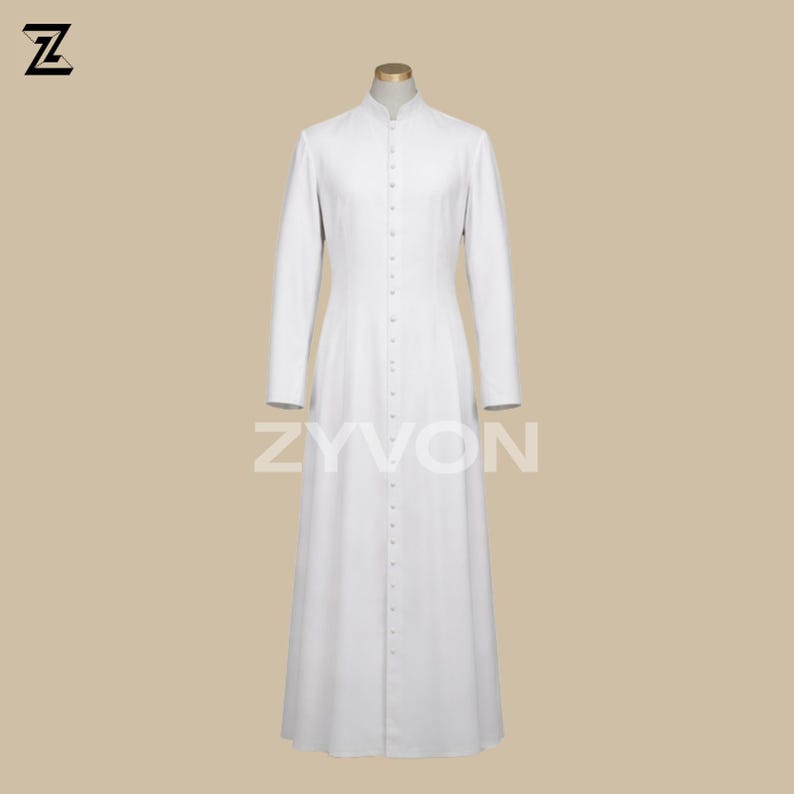 Pu&ograve; includere: Una lunga veste bianca abbottonata con colletto alla coreana. La veste ha maniche lunghe e orlo a terra. Il marchio "ZYVON" &egrave; stampato in bianco sulla parte inferiore della veste. La veste &egrave; esposta su un manichino.