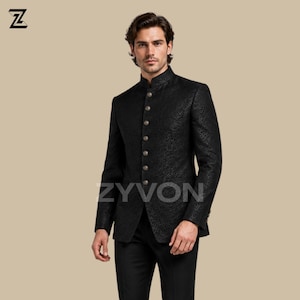 May include: A black band collar jacket with a delicate floral design and gold buttons. The jacket is tailored and worn with black trousers. The brand name "ZYVON" is displayed on the jacket.