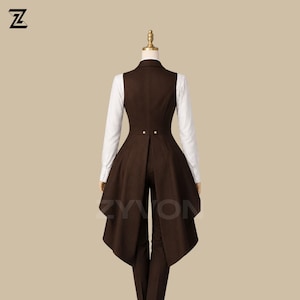 May include: A brown vest with a long, flared back, paired with matching pants and a white collared shirt. The vest features two gold buttons and a tailored fit. The outfit is displayed on a mannequin.