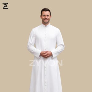 Pu&ograve; includere: Una veste clericale bianca a maniche lunghe con colletto alla coreana e abbottonatura frontale. La veste &egrave; indossata da una persona con le mani giunte davanti. Il marchio "ZYVON" &egrave; stampato in bianco nella parte inferiore.