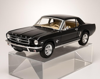 May include: A black 1965 Ford Mustang model car with chrome accents and a tan interior. The model sits on a clear, angled display stand. The car has the Ford and Mustang emblems.