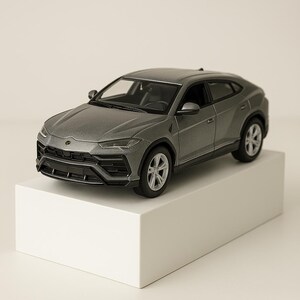 May include: A gray die-cast model of a luxury SUV. The miniature car is displayed on a white block, showcasing its detailed design, including headlights, wheels, and a sleek body. The vehicle is a metallic gray color.