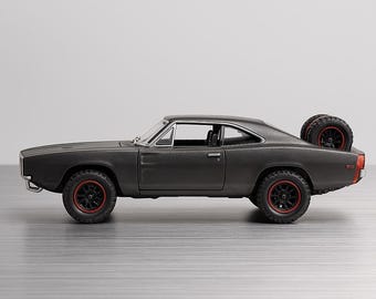 Könnte beinhalten: Ein dunkelgraues Modellauto mit schwarzen Rädern und roten Felgen. Das Auto hat einen Ersatzreifen auf der Rückseite montiert. Das Auto ist ein klassisches Muscle-Car-Design.