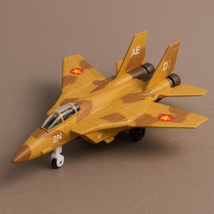 May include: A tan and brown toy airplane with a camouflage pattern. The toy plane has the letters "AE" and "D!" on the tail fins, and the number "2N" on the nose. Red star emblems are on the wings.
