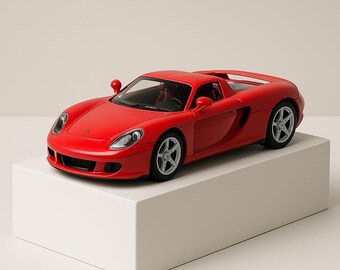 May include: A red sports car model with silver wheels is displayed on a white block. The car has a sleek design with visible headlights, side mirrors, and a detailed interior. The model is a vibrant red color.