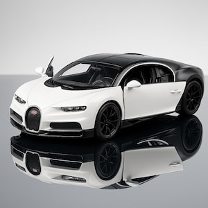 May include: A white and black model car with the door open, showcasing the interior. The car has black wheels and a black roof. The car's front features a red emblem. The car is reflected on a glossy surface.