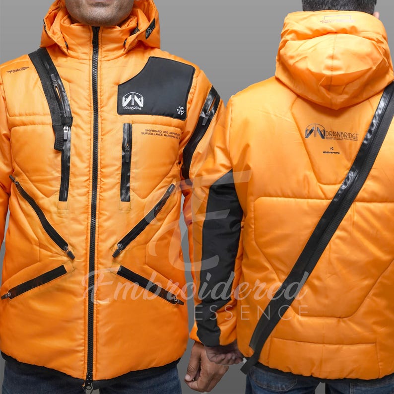 May include: An orange winter jacket with black accents, zippers, and a hood. The jacket features the text "DRANDRIDGE" and "Embroidered Essence". The jacket has a quilted design and a black shoulder strap.